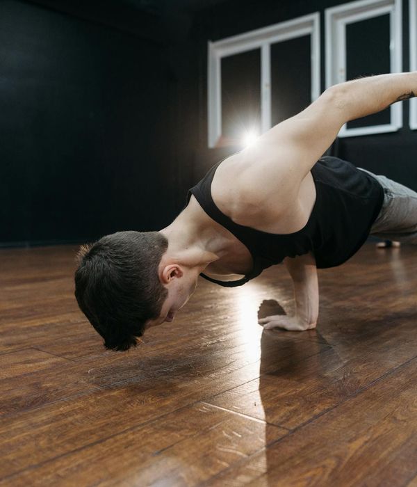 Man practicing gentle strength movements in a dark studio